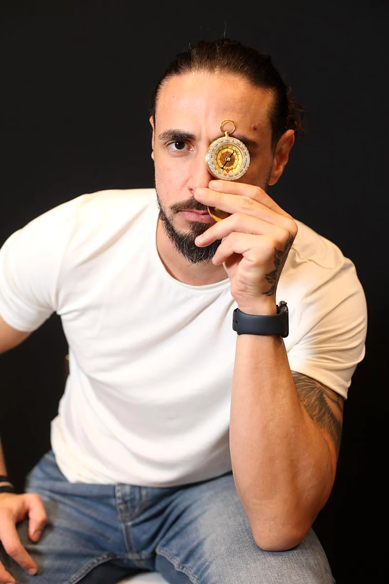William Gutierrez, criador do Método Bússola, segurando uma bússola dourada junto ao rosto